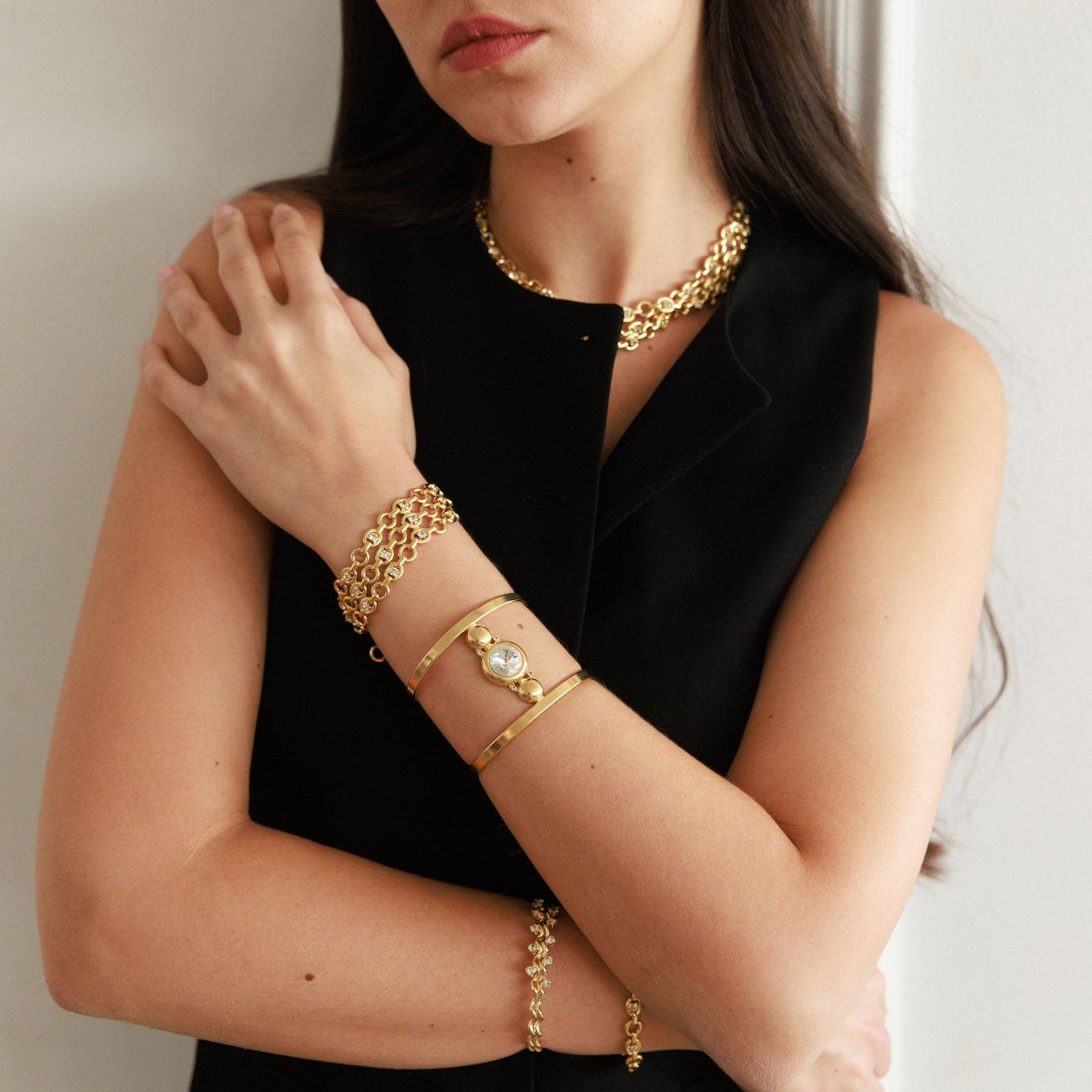 Woman wearing gold jewelry against a neutral background