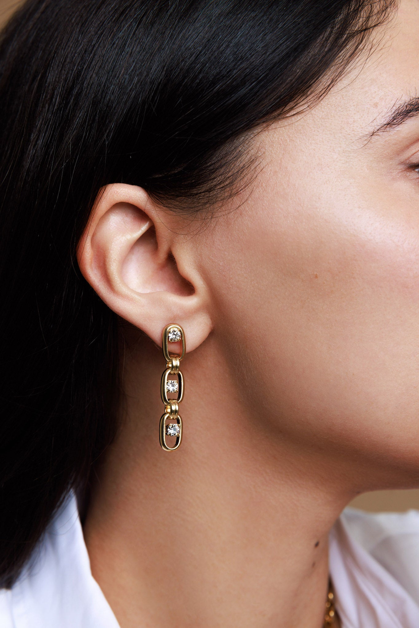 Close-up of a person wearing gold hoop earrings with a blurred background