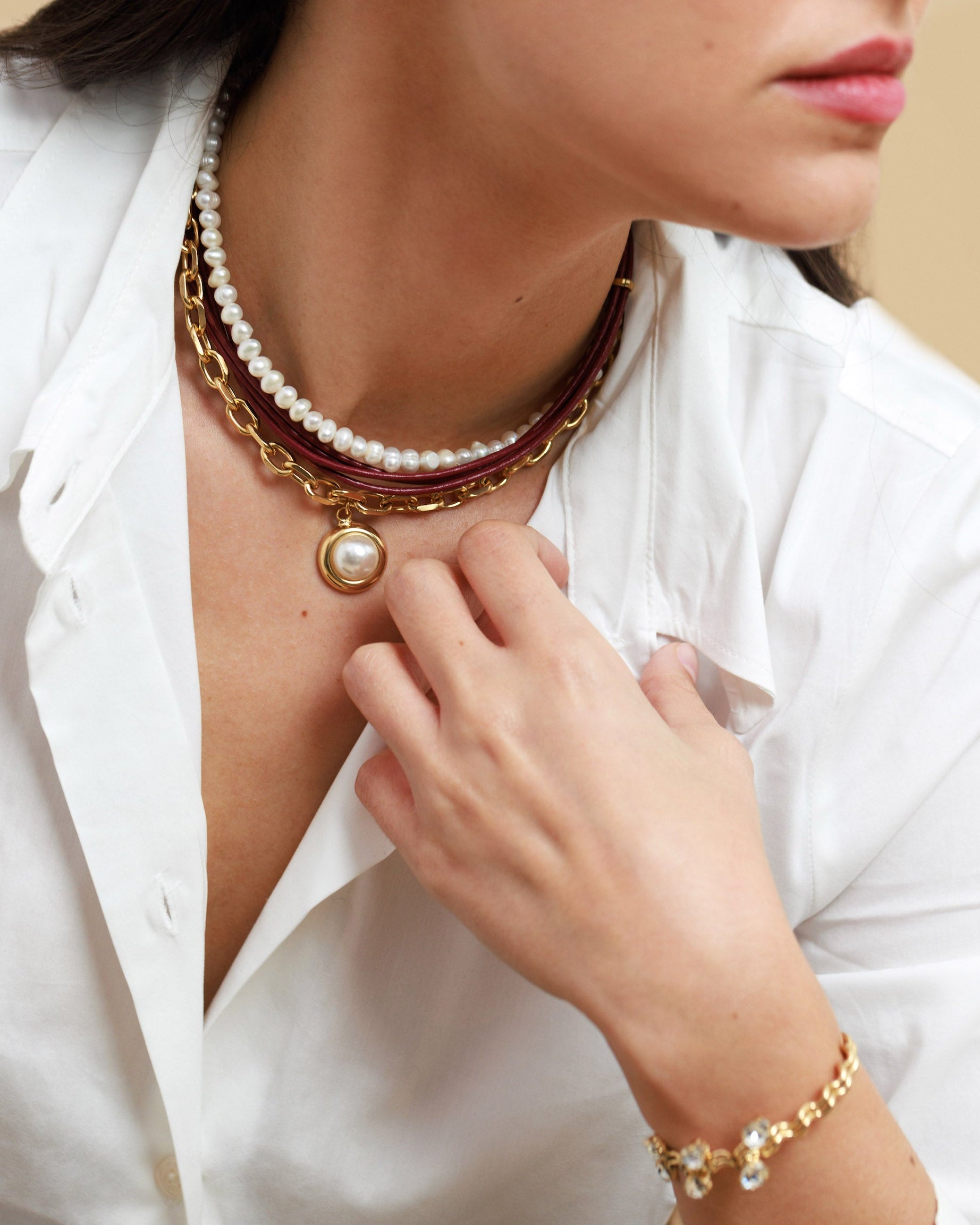 Woman wearing a pearl necklace and bracelet against a beige background