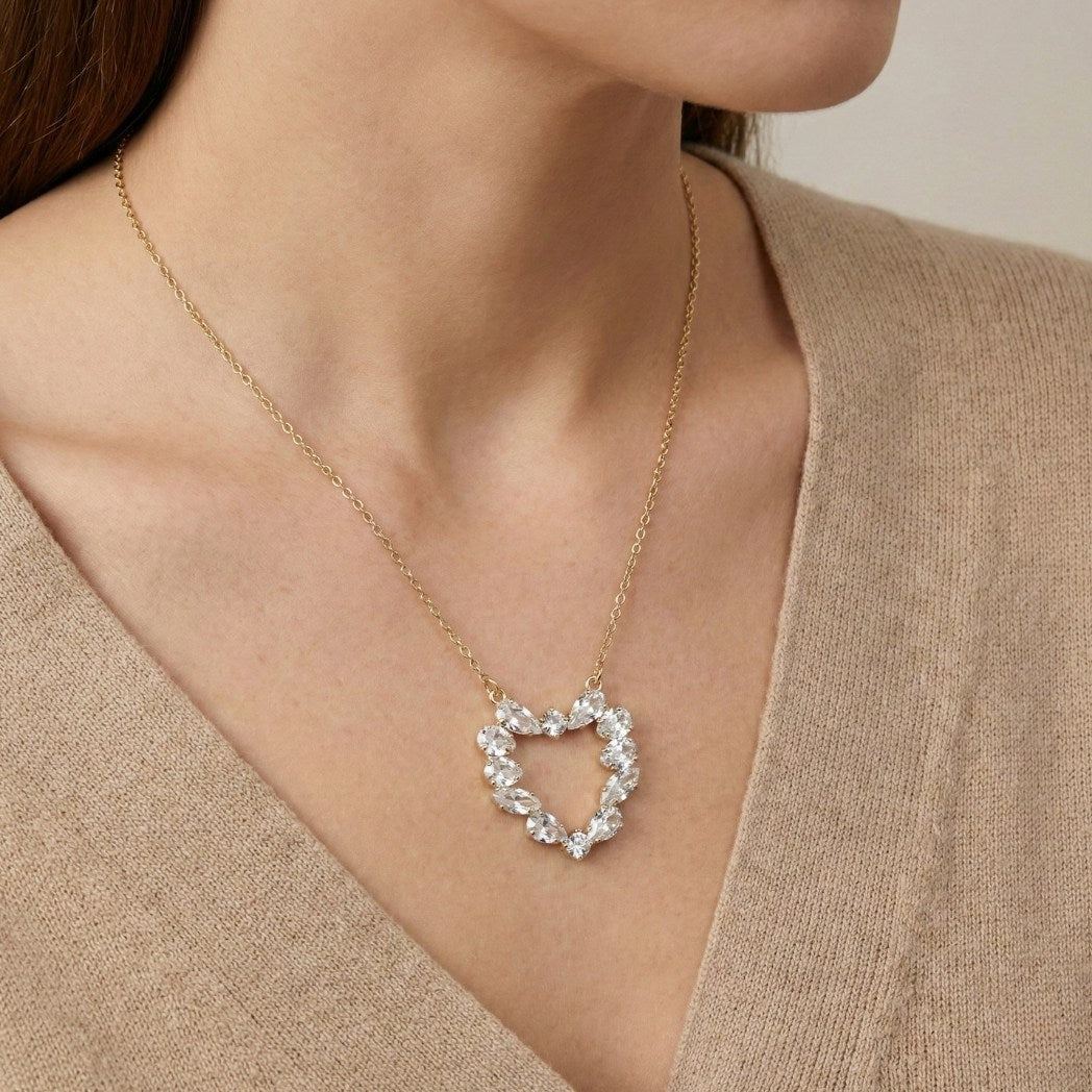 Heart-shaped diamond necklace worn by a person in a beige top