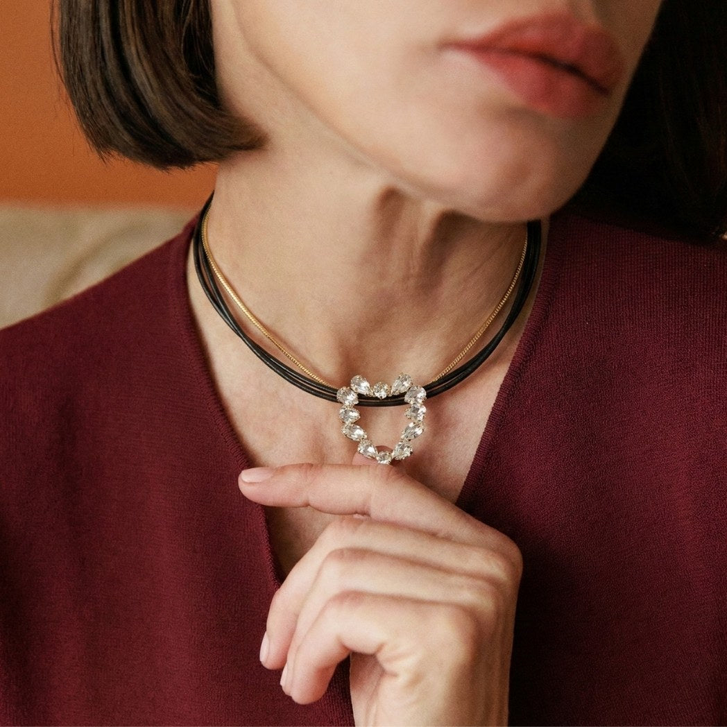 Close-up of a person wearing a necklace with a heart-shaped pendant.